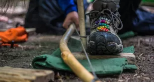 Person creating fire with bow drill technique.