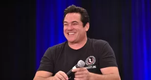 Dean Cain joins ice, Smiling speaker holding microphone on stage
