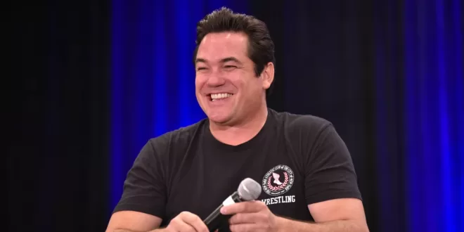 Dean Cain joins ice, Smiling speaker holding microphone on stage