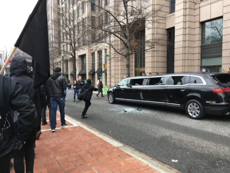 Protesters damage a limousine during a demonstration.
